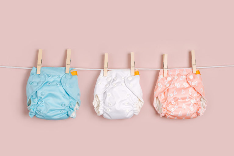 Reusable cloth baby diapers drying on a clothes line.