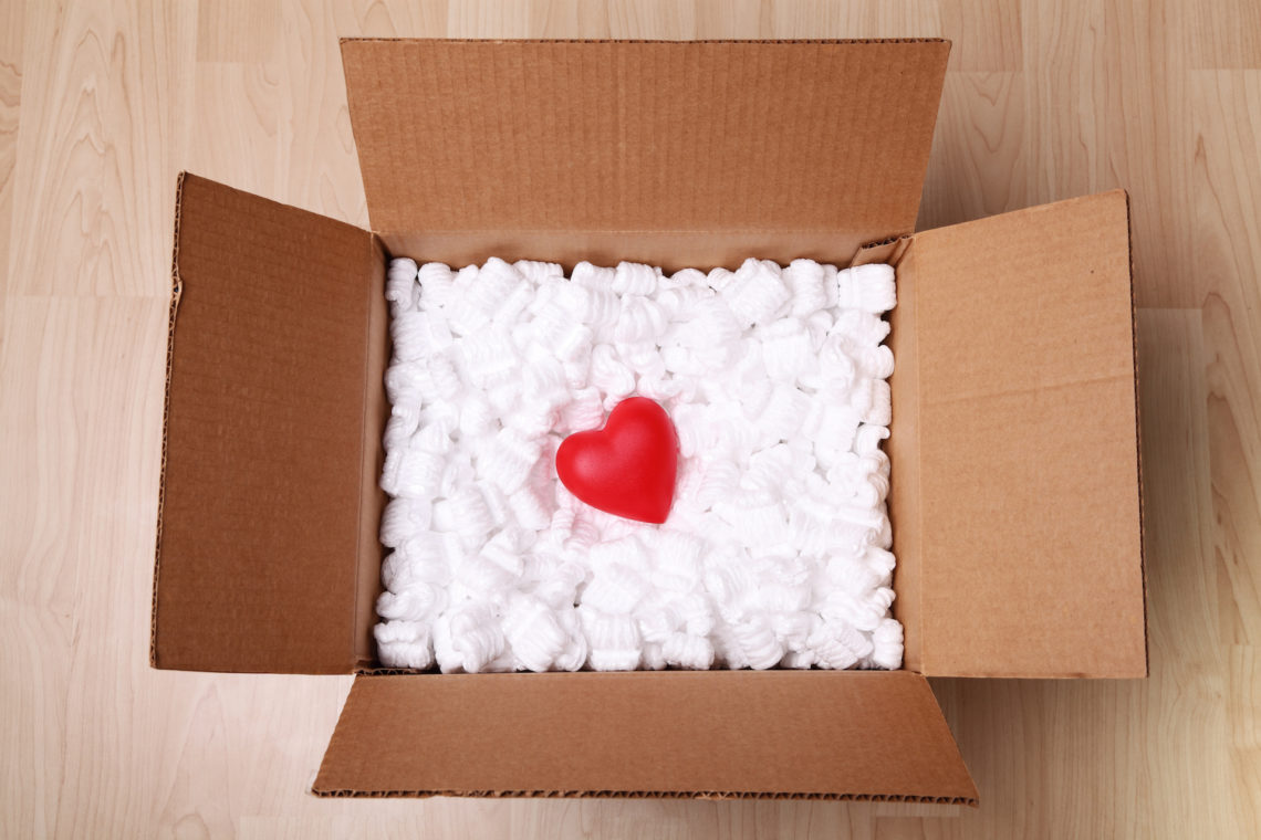A red heart in acardboard box full of packing peanuts